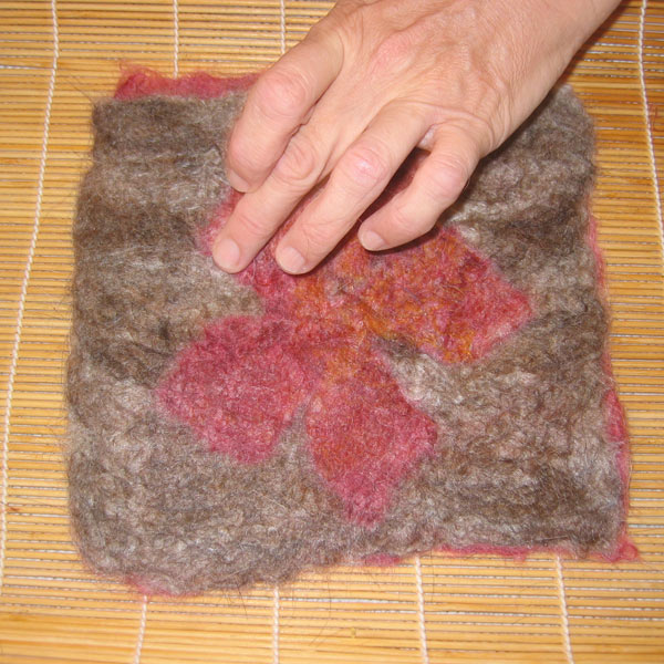 A piece of felted material that has a a coloured edge and a flower graphic in the middle